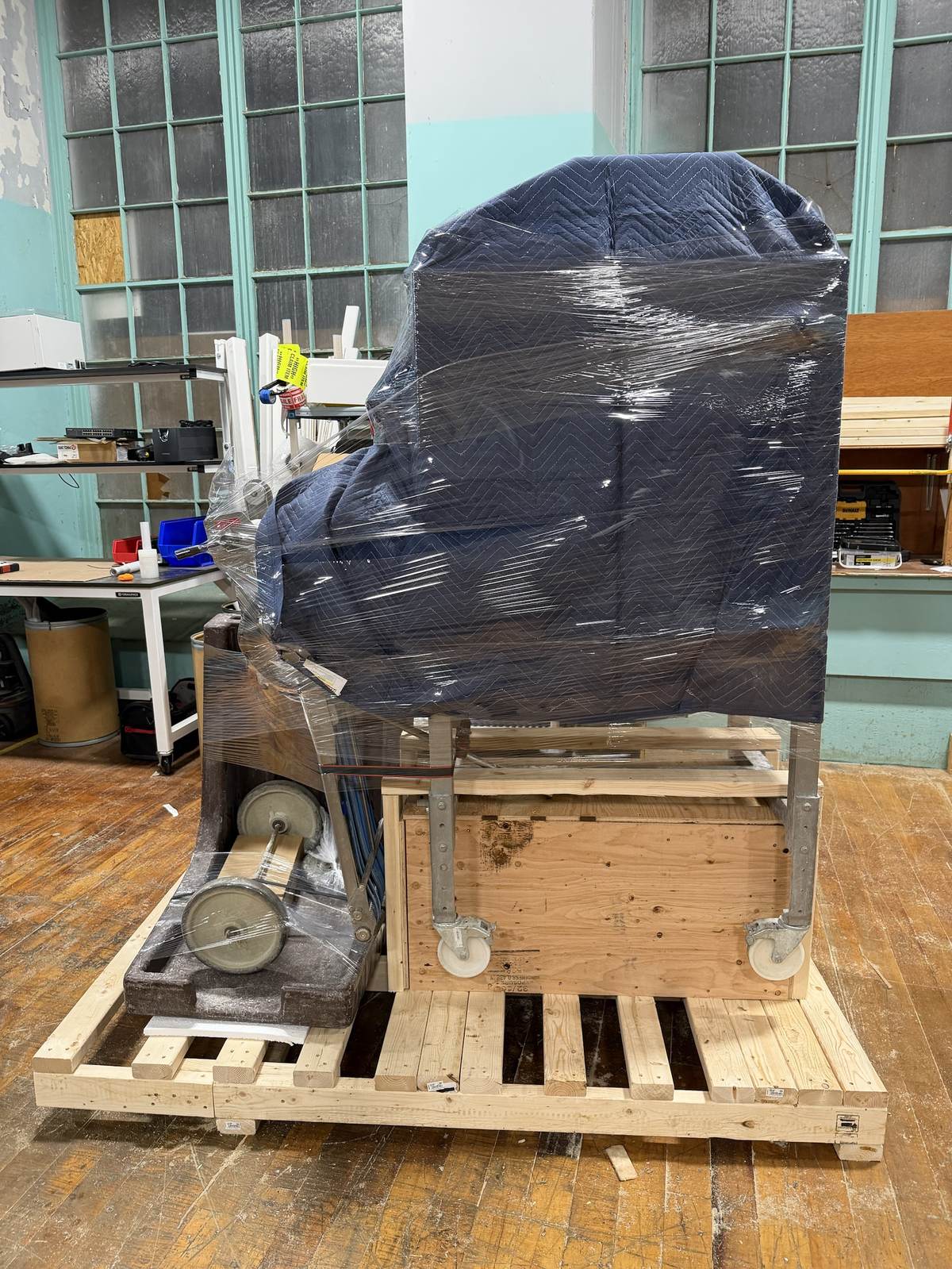 A machine wrapped in quilted moving blankets inside a wood crate.