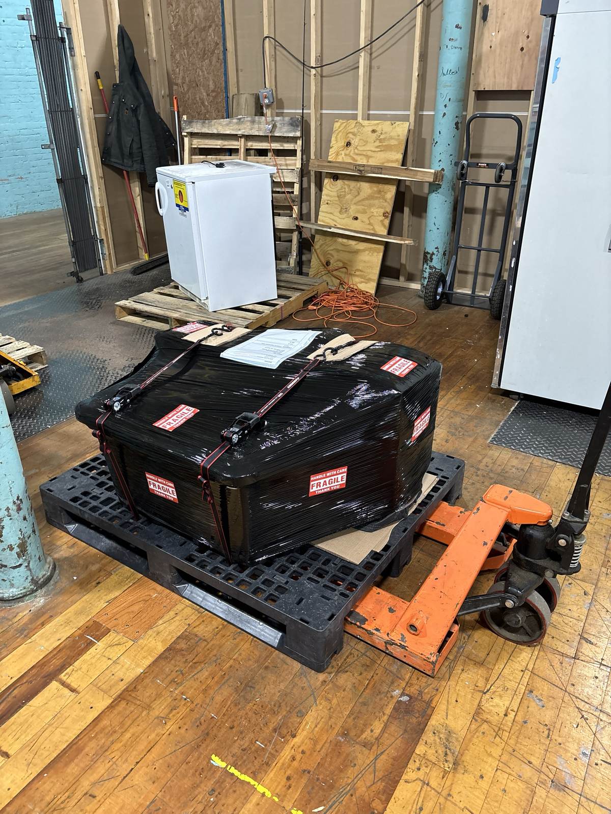 Equipment wrapped and staged on a pallet jack in the shop.