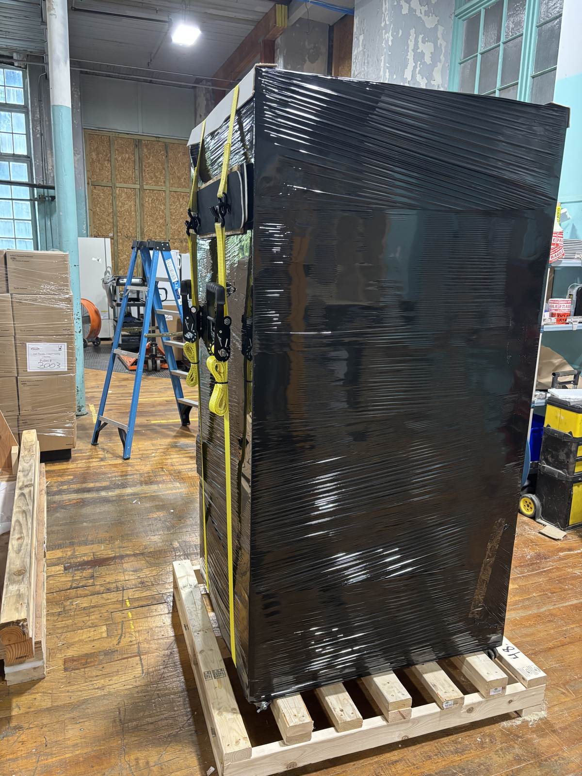 A shrink-wrapped, strapped pallet marked and ready for LTL freight pickup.